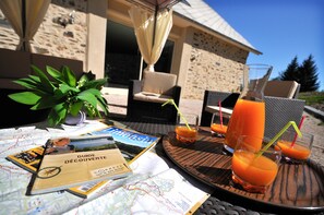 A table with a map, a guidebook, and two glasses of orange juice with straws. - Océane Guest Room with Wi-Fi and Air Conditioning (Perpezac-le-Noir)