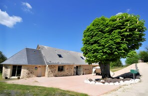 A stone building with a sloped roof and a large tree in front. - Océane Guest Room with Wi-Fi and Air Conditioning (Perpezac-le-Noir)