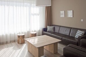 A modern living room with a sofa, a coffee table, and two side tables. - Holiday apartment with 3 bedrooms (Westkapelle)