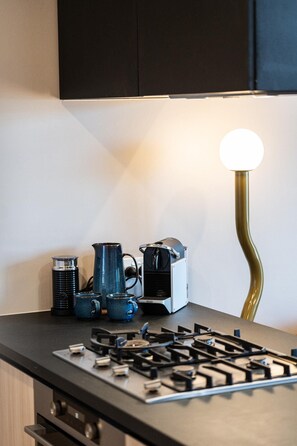 A kitchen counter with a gas stove, a coffee maker, and a kettle. - StayCentral - The Islington - Islington Street, Collingwood - 1 Bedrooms, 1 Bed, 1 Bath, 1 secure undercover parking (stacker - induction required). (Collingwood)