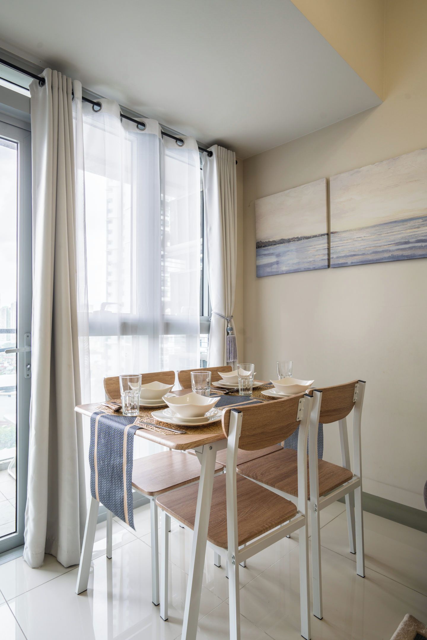 A dining area with a table set for four, chairs, and a view of the city through large windows.