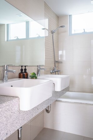 Ein modernes Badezimmer mit zwei Waschbecken, einer Dusche und einer Badewanne.