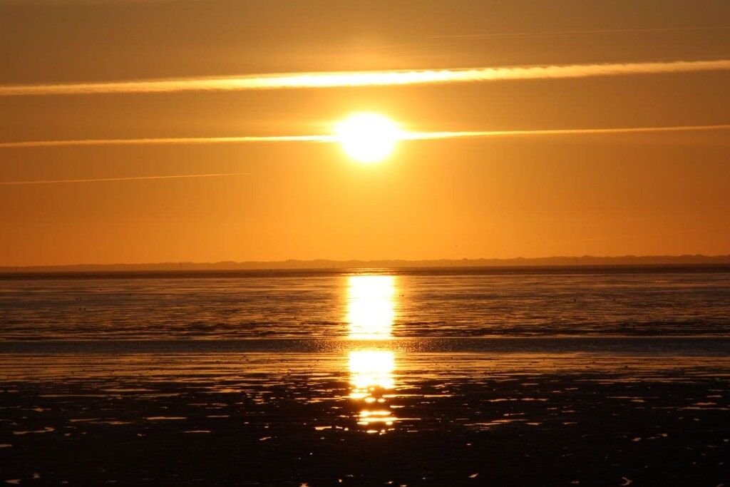 A sunset over a body of water with a clear sky.
