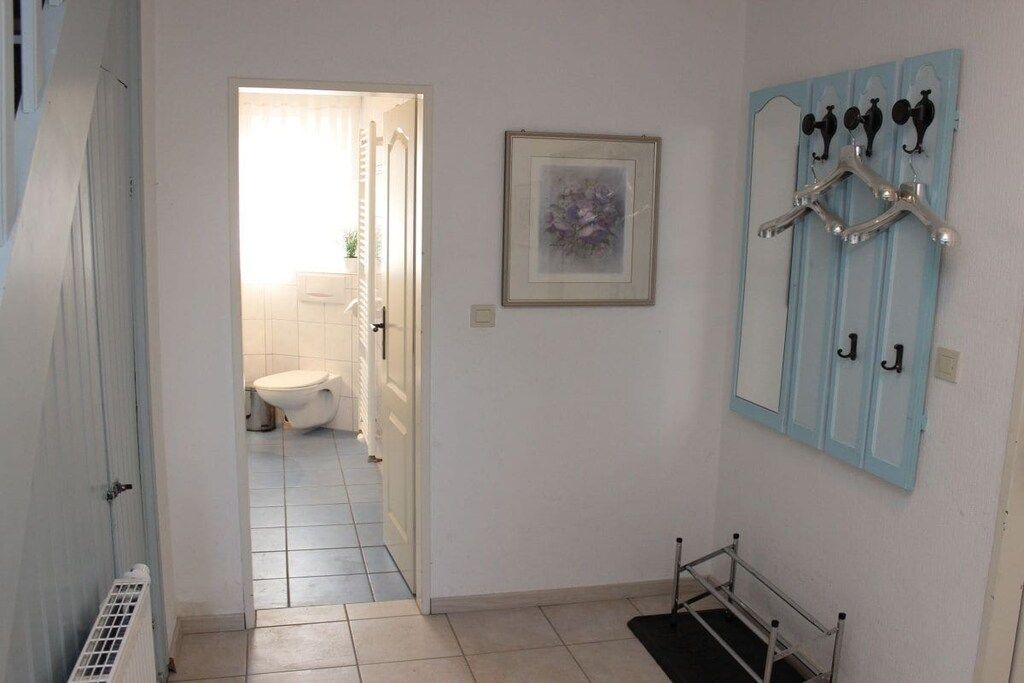 Une salle de bain avec des toilettes, une douche et un lavabo. Un tableau encadré est accroché au mur, et il y a un porte-serviettes avec des crochets.