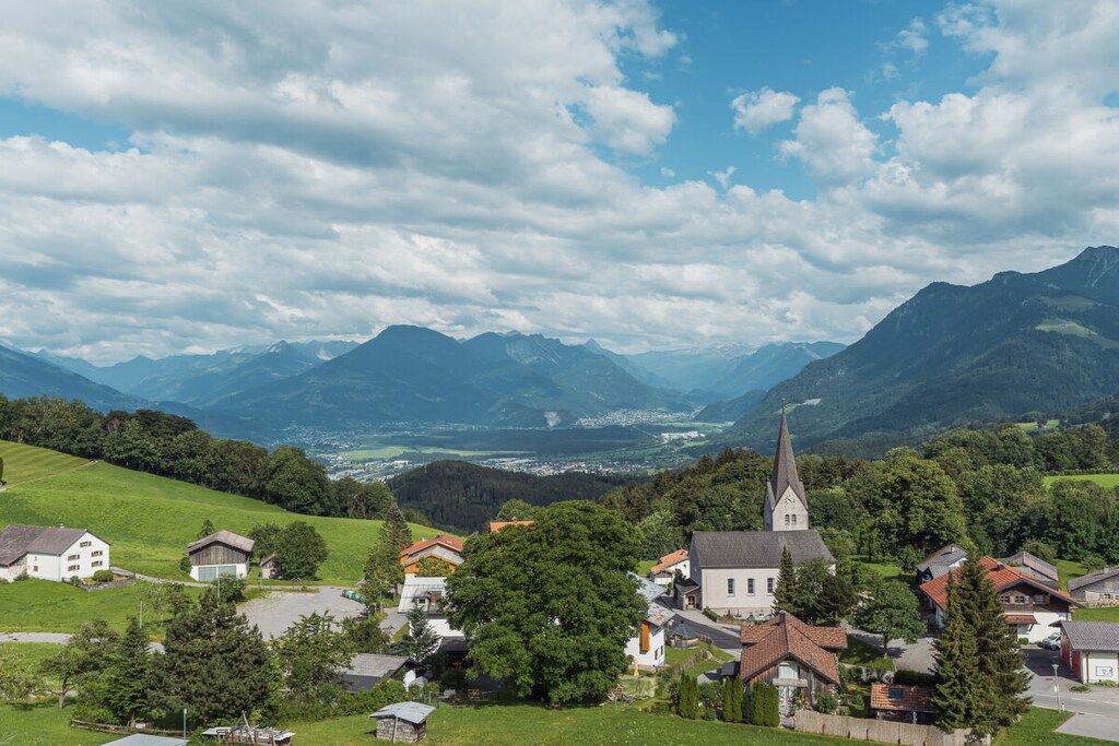 Ein Dorf mit Häusern, einer Kirche und Bergen im Hintergrund.