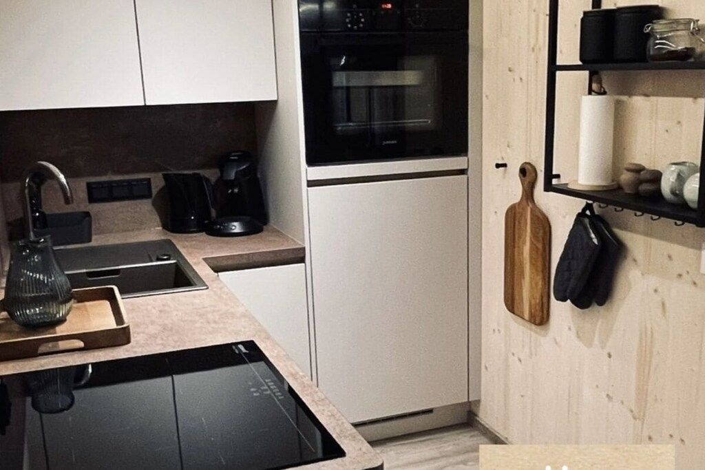 Une cuisine moderne équipée d’un four encastré, d’une machine à café et d’un porte-couteaux fixé au mur.