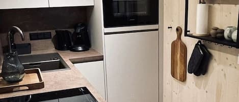 A modern kitchen with a built-in oven, a coffee maker, and a knife block on the wall.
