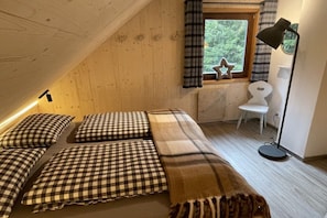 A cozy room with a sloped ceiling, a bed with checkered bedding, a star-shaped decoration, a chair, and a floor lamp. - Ski lodge in Ebene Reichenau with sauna (Ebene Reichenau)