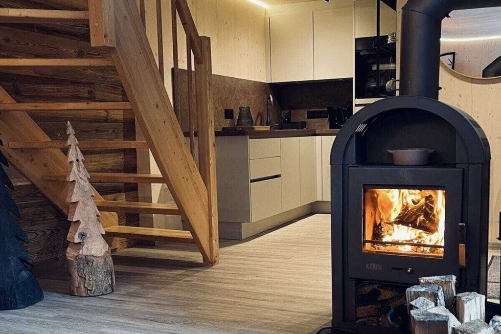 Eine moderne Küche mit Kaminofen, einer Holztreppe und einem kleinen Weihnachtsbaum.