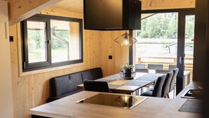 Moderni keittiö, jossa on keskellä sijaitseva saareke, puuseinät ja suuret ikkunat.