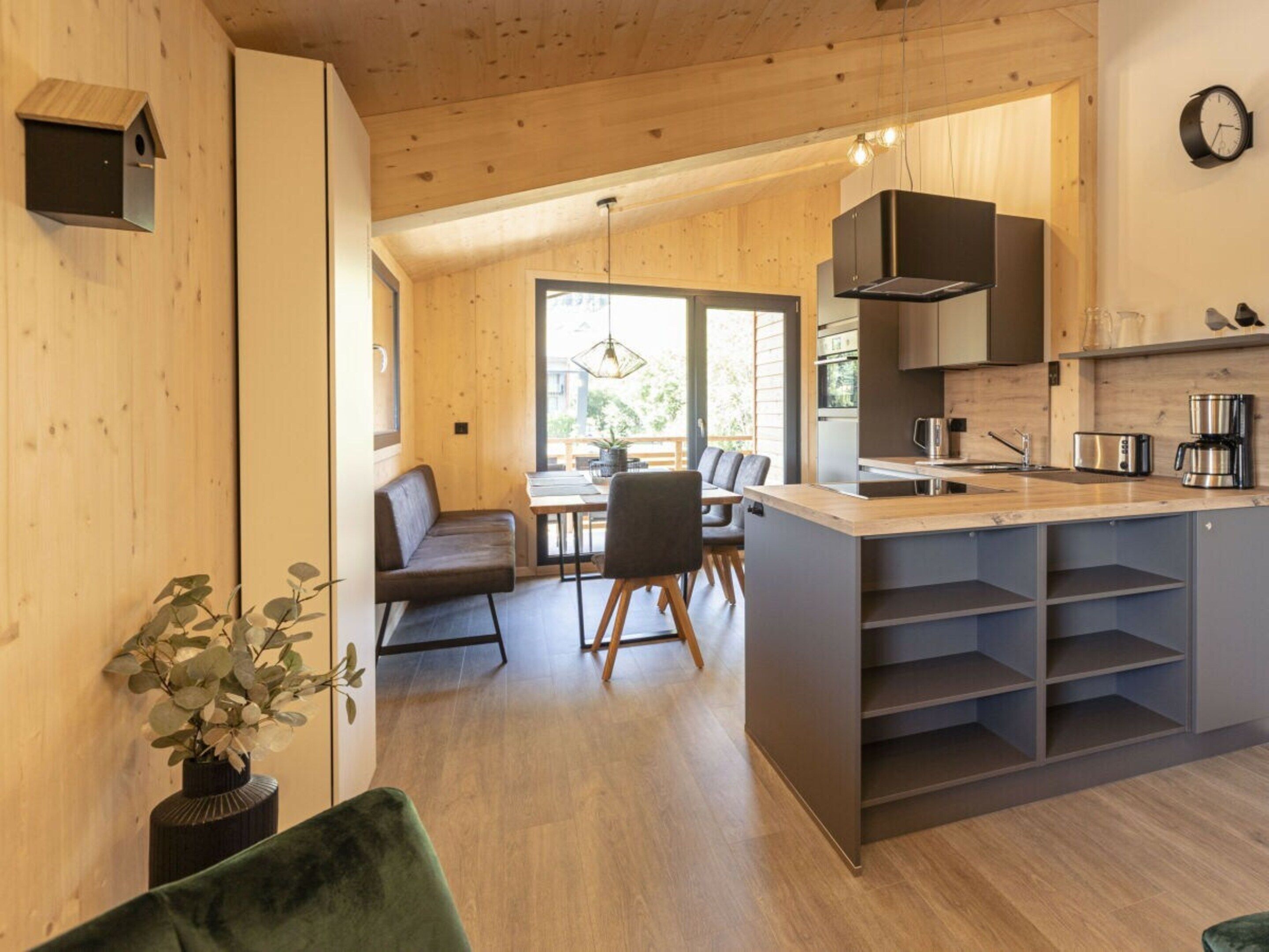 Una cocina moderna con una isla central, armarios de madera y un comedor con banco y sillas.