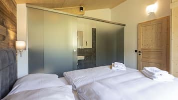 Un dormitorio con dos camas, techo de madera, armario con puerta corredera, espejo de baño y una pila de toallas.