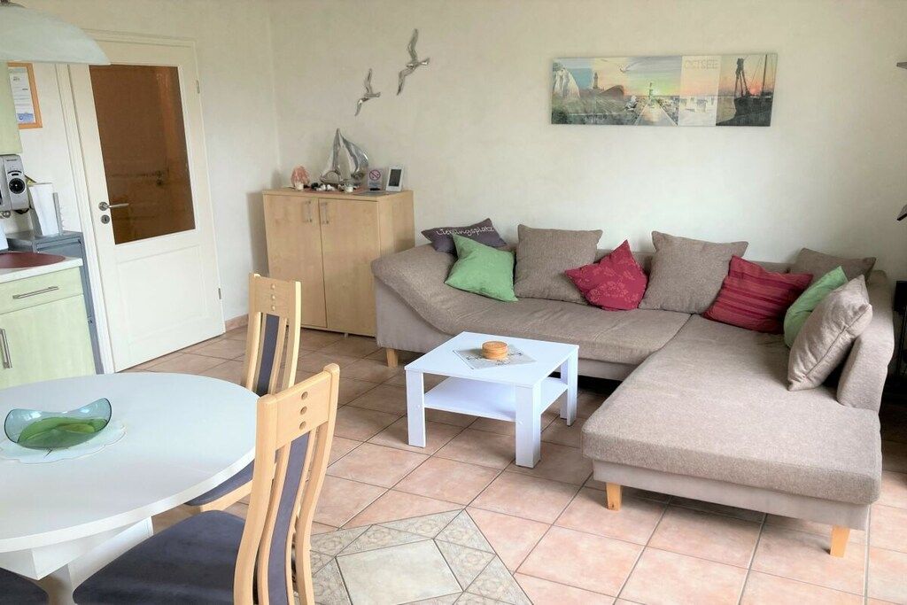 Ein Wohnzimmer mit einer Couch, einem kleinen weißen Tisch, einem Sessel und einem Schrank.