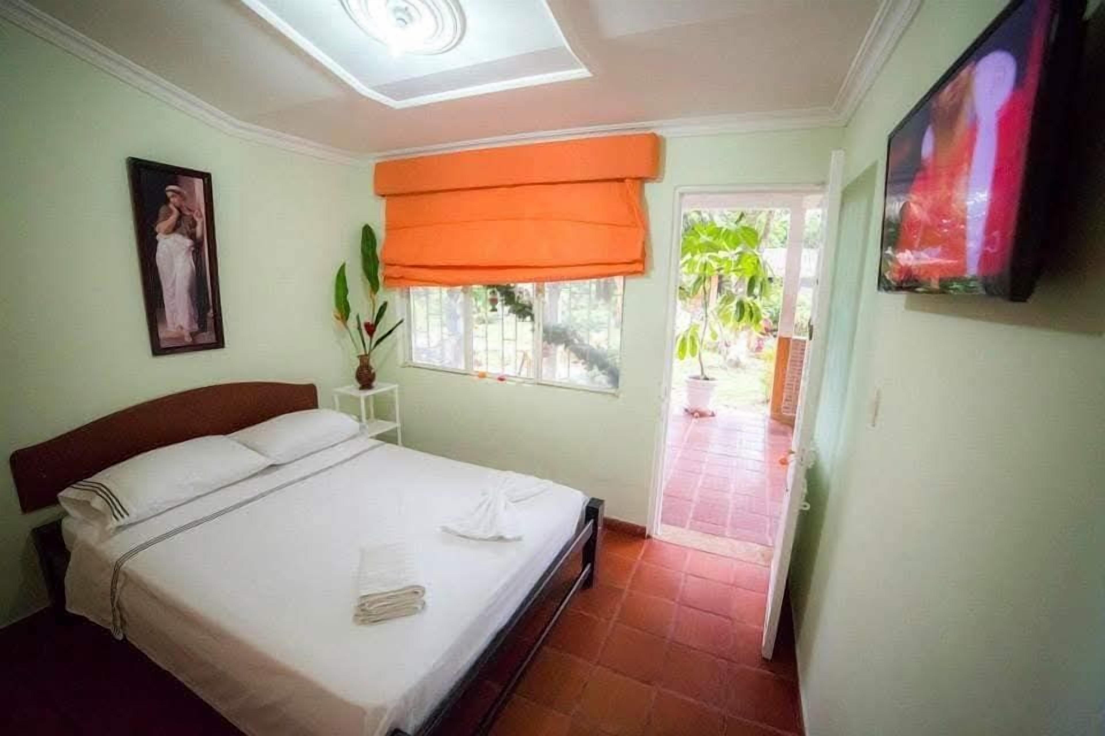Un dormitorio con cama, ventana con vistas, televisión y puerta que da al exterior.