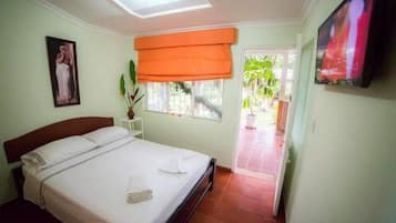 Un dormitorio con cama, ventana con vistas, televisión y puerta que da al exterior.