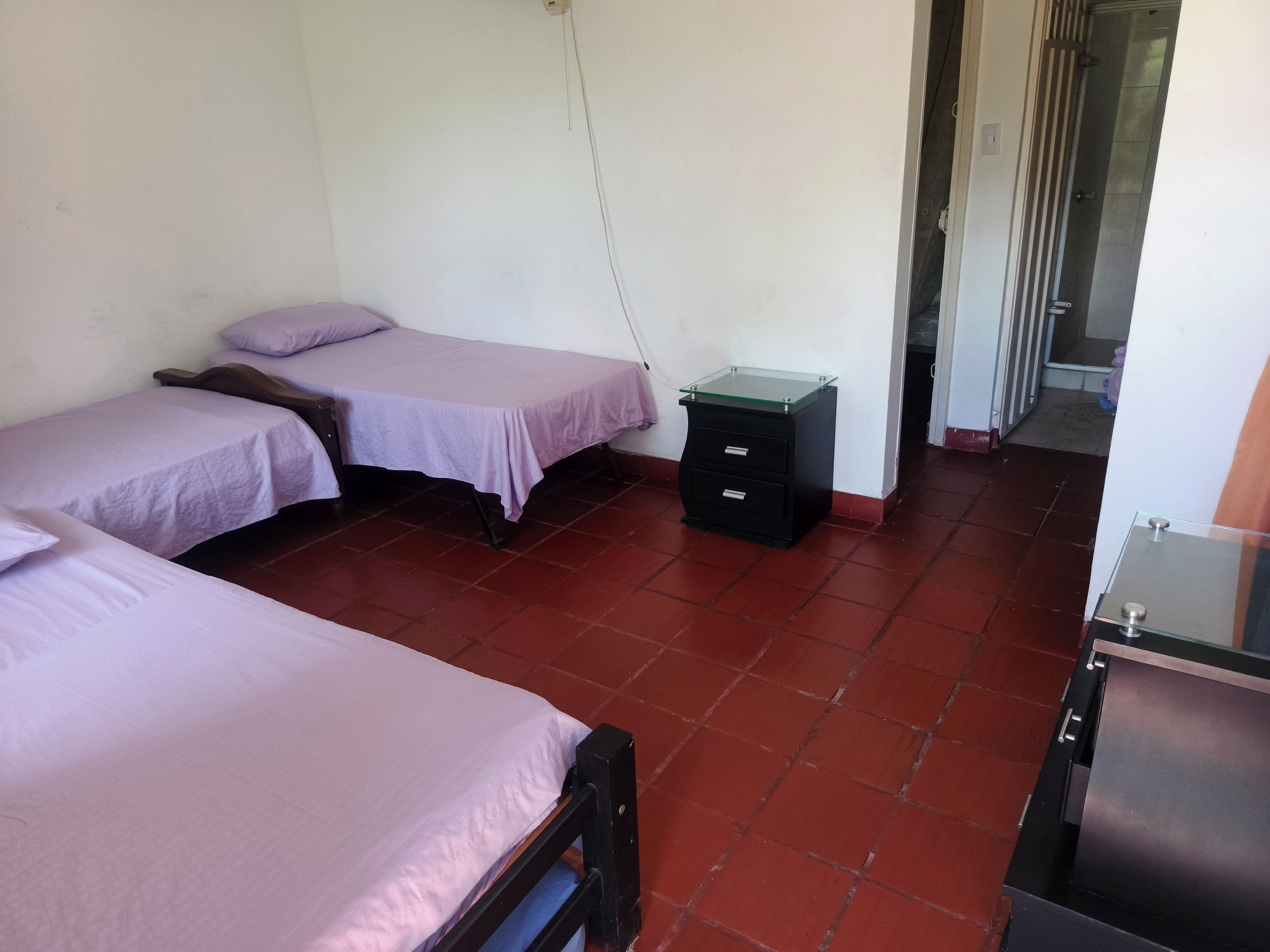 Une chambre avec deux lits, une petite table de chevet et une armoire.