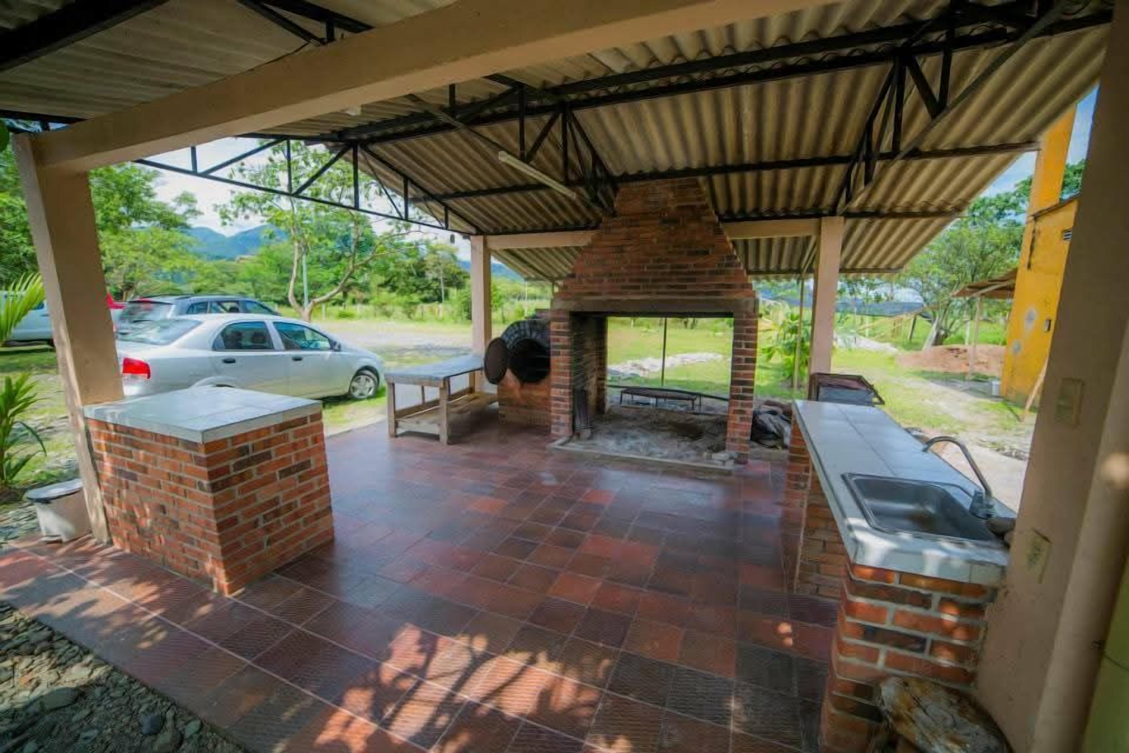 Un patio al aire libre con una zona de parrillada de ladrillo, un lavamanos y un área de estar cubierta.