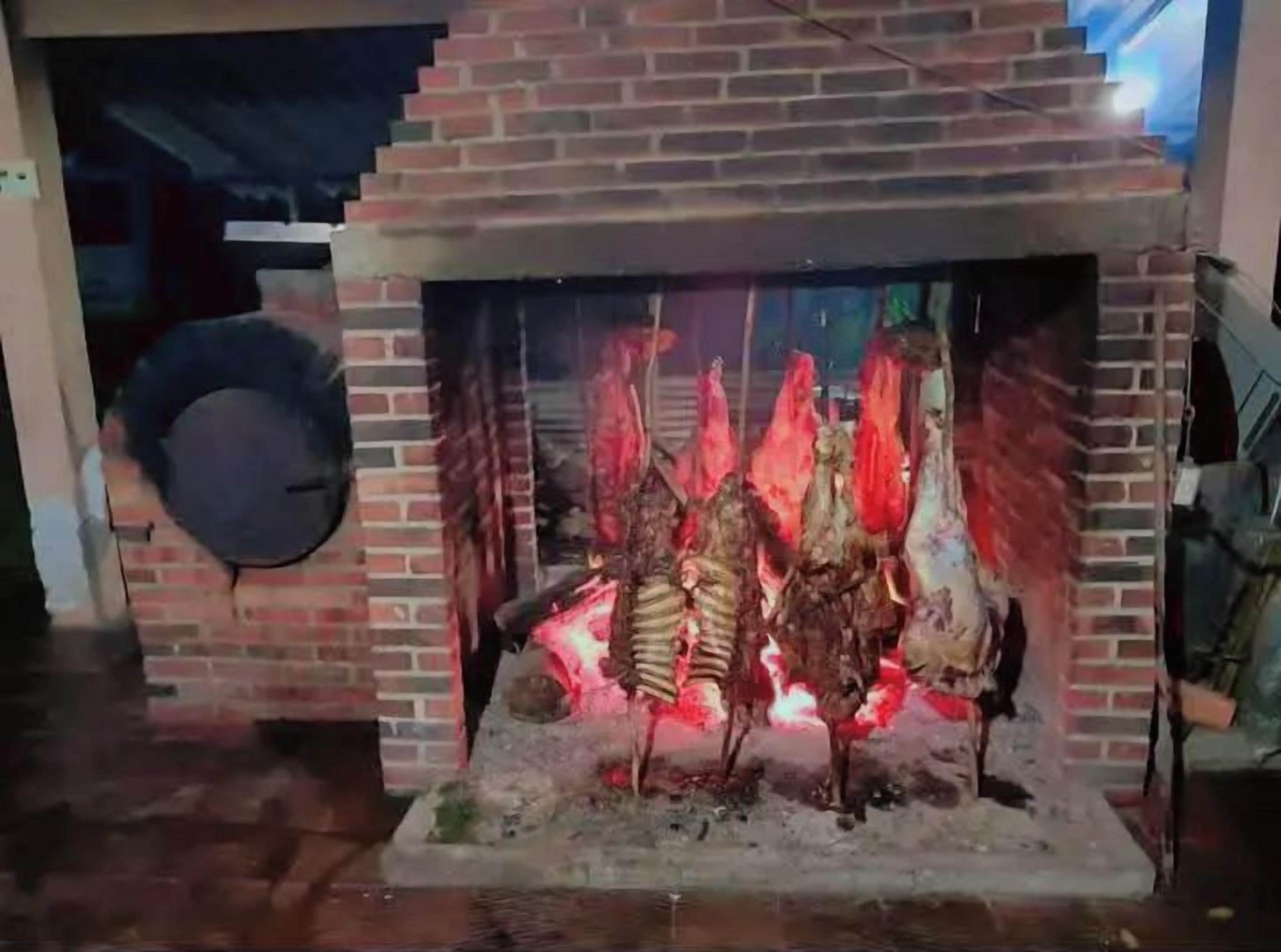 Una chimenea de ladrillo con fuego encendido, rodeada por un muro de ladrillo.