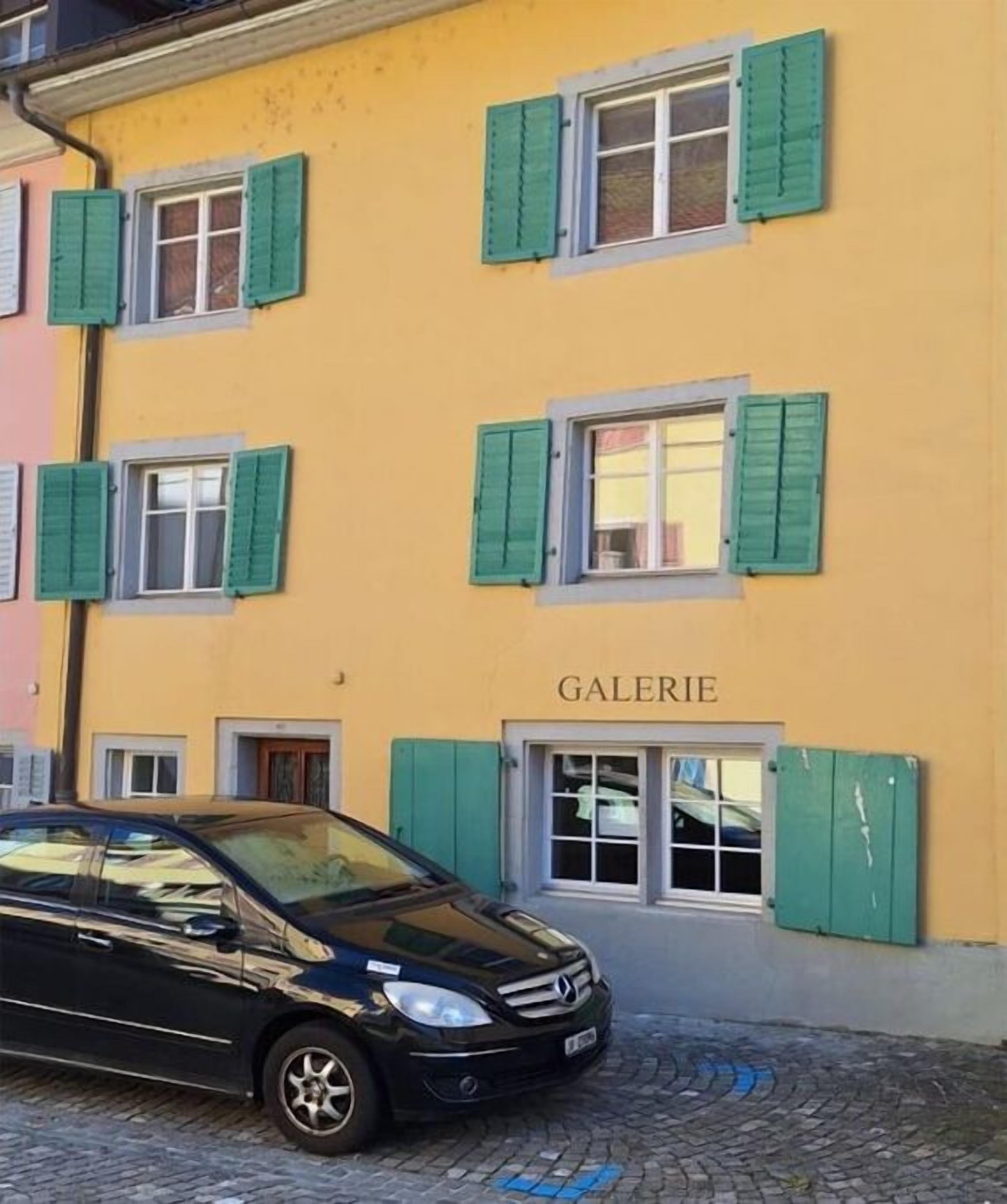 Un edificio con facciata gialla e persiane verdi, con la scritta 'GALERIE'.