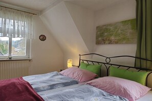 A bedroom with a bed, a window, a radiator, and a wall-mounted artwork. - Holiday apartment with 2 bedrooms (Bad Schandau)