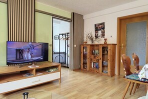 A living room with a television, wooden entertainment unit, and a bookshelf. - Holiday apartment with 2 bedrooms (Bad Schandau)