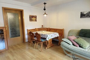 A dining area with a wooden table and chairs, a wooden bench, and a sofa with cushions. - Holiday apartment with 2 bedrooms (Bad Schandau)