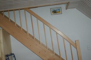 A wooden staircase with a handrail, a picture on the wall, and a door at the bottom. - Holiday apartment with 1 bedroom (Alt-Schwerin)