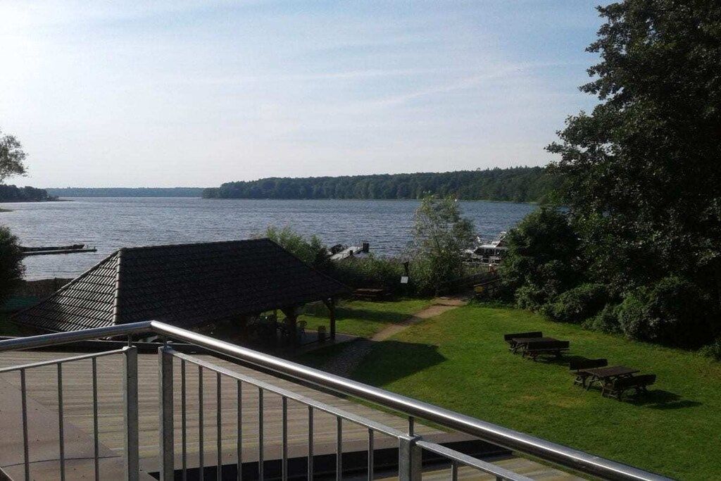A lakeside view with a gazebo, picnic tables, and a boat dock.