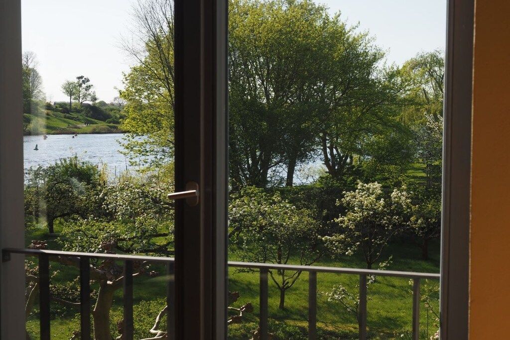 A view from a window overlooking a lake with trees and a grassy area.