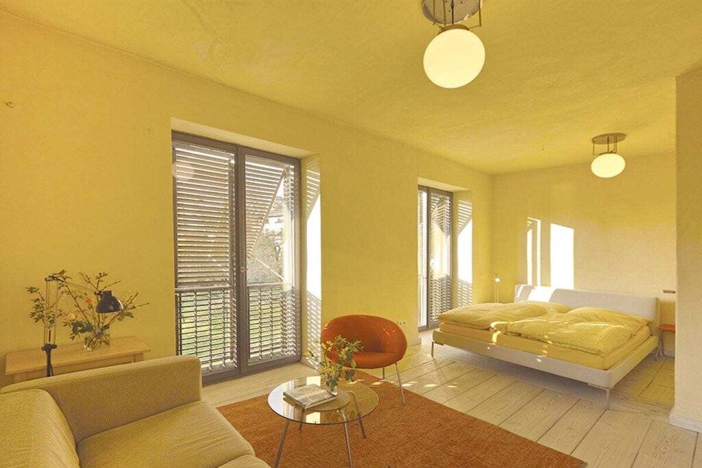 Et moderne soveværelse med seng, sofa, stol og et lille bord.