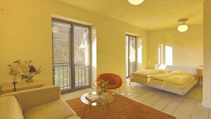 A modern bedroom with a bed, a sofa, a chair, and a small table. - Holiday apartment with 1 bedroom (Potsdam)