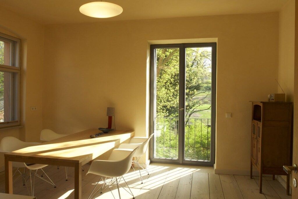 A room with a large sliding glass door, a wooden table with chairs, and a small cabinet.