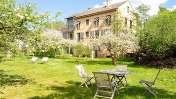 A two-story building with a garden patio featuring outdoor furniture.