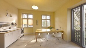 A kitchen with a dining area, a large window, and a view of the outside. - Holiday apartment with 1 bedroom (Potsdam)