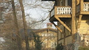 A historic building with a stone facade, a wooden balcony, and a small bridge over a pond. - Holiday apartment with 1 bedroom (Potsdam)