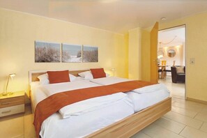 A modern hotel room with a large bed, bedside tables, and a view of the dining area. - Holiday apartment with 2 bedrooms (Lübeck)