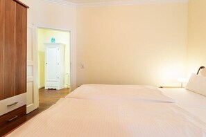 Een hotelkamer met een bed, een kledingkast en een deur naar een andere kamer.