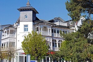 A multi-story building with a prominent tower, balconies, and a white facade. - Holiday apartment with 1 bedroom (Ostseebad Binz)