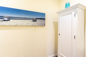 A room with a beach painting on the wall, a white cabinet, and a door. - Holiday apartment with 1 bedroom (Ostseebad Binz)