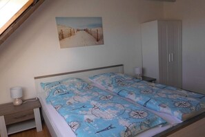 Un dormitorio con cama, mesita de noche, lámpara, armario y un cuadro en la pared.