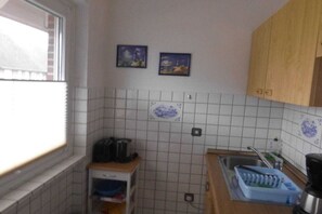 Eine Küche mit Fenster, gefliestem Spritzschutz und Holzschränken.