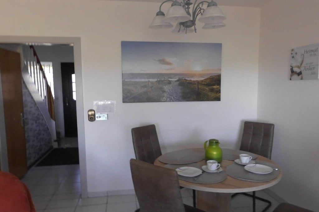 A dining area with a round table, chairs, a painting, and a door with a lock.