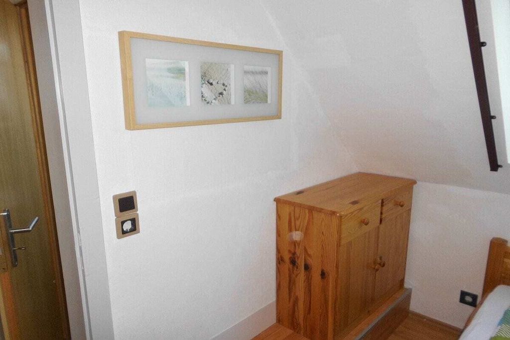 Een kamer met een houten kast, een lijst met een afbeelding aan de muur en een deur.