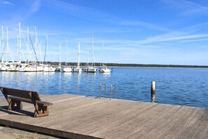 A wooden dock with a bench, a clear blue sky, and sailboats docked in the water. - Holiday home in Breege with swimming pool (Breege)