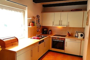 A compact kitchen with white cabinets, a built-in oven, a dishwasher, and a window providing natural light. - Holiday home with 2 bedrooms (Göhren-Lebbin)