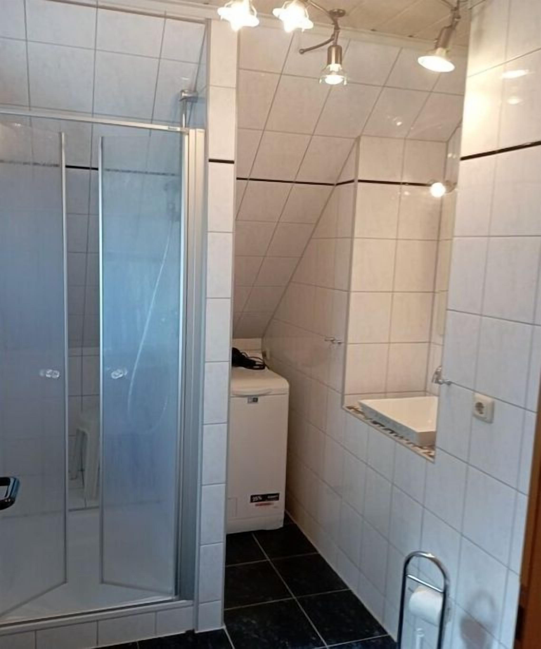 Kylpyhuone, jossa on lasiseinäinen suihkukaappi, wc ja pesuallas.