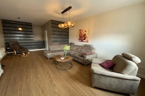 A modern living room with a sectional sofa, a rocking chair, and a coffee table. - Holiday apartment with 1 bedroom (Waren \/ Müritz)