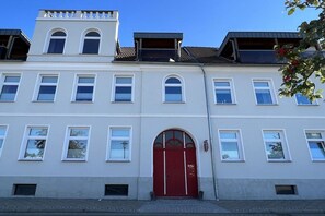A multi-story building with a red door, multiple windows, and a balcony. - Holiday apartment with 1 bedroom (Waren \/ Müritz)