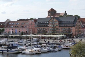 A marina with boats docked, a building with a tower, and outdoor seating areas. - Holiday apartment with 1 bedroom (Waren \/ Müritz)