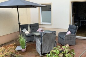 An outdoor patio with wicker furniture, a table, and a potted plant. - Holiday apartment with 1 bedroom (Waren \/ Müritz)